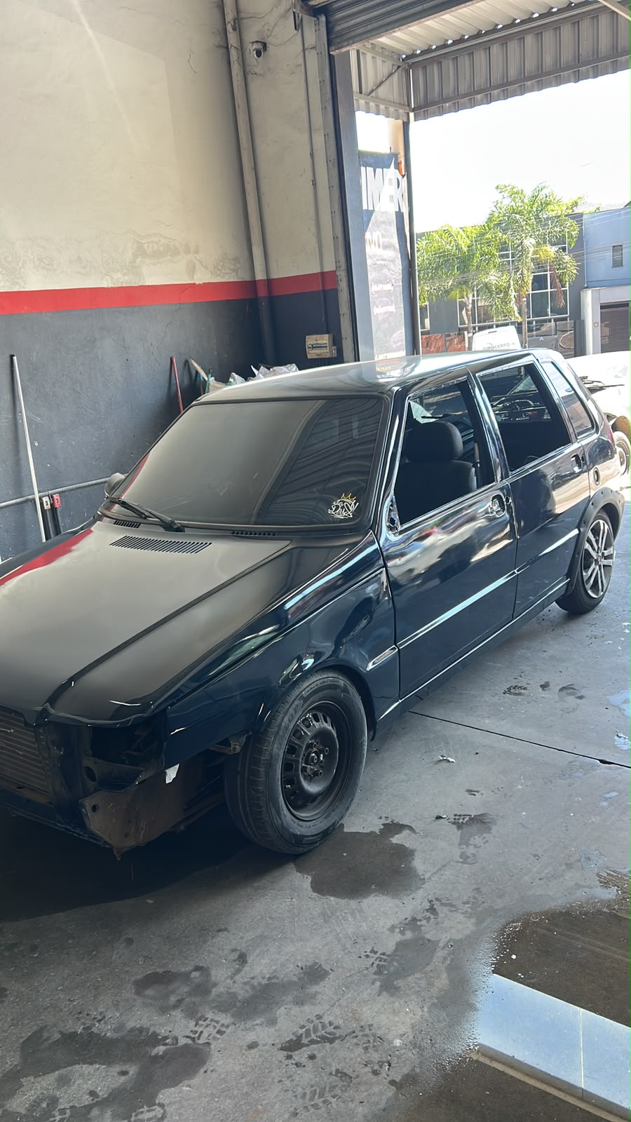 Fiat Uno preto com a pintura recém-finalizada na oficina
