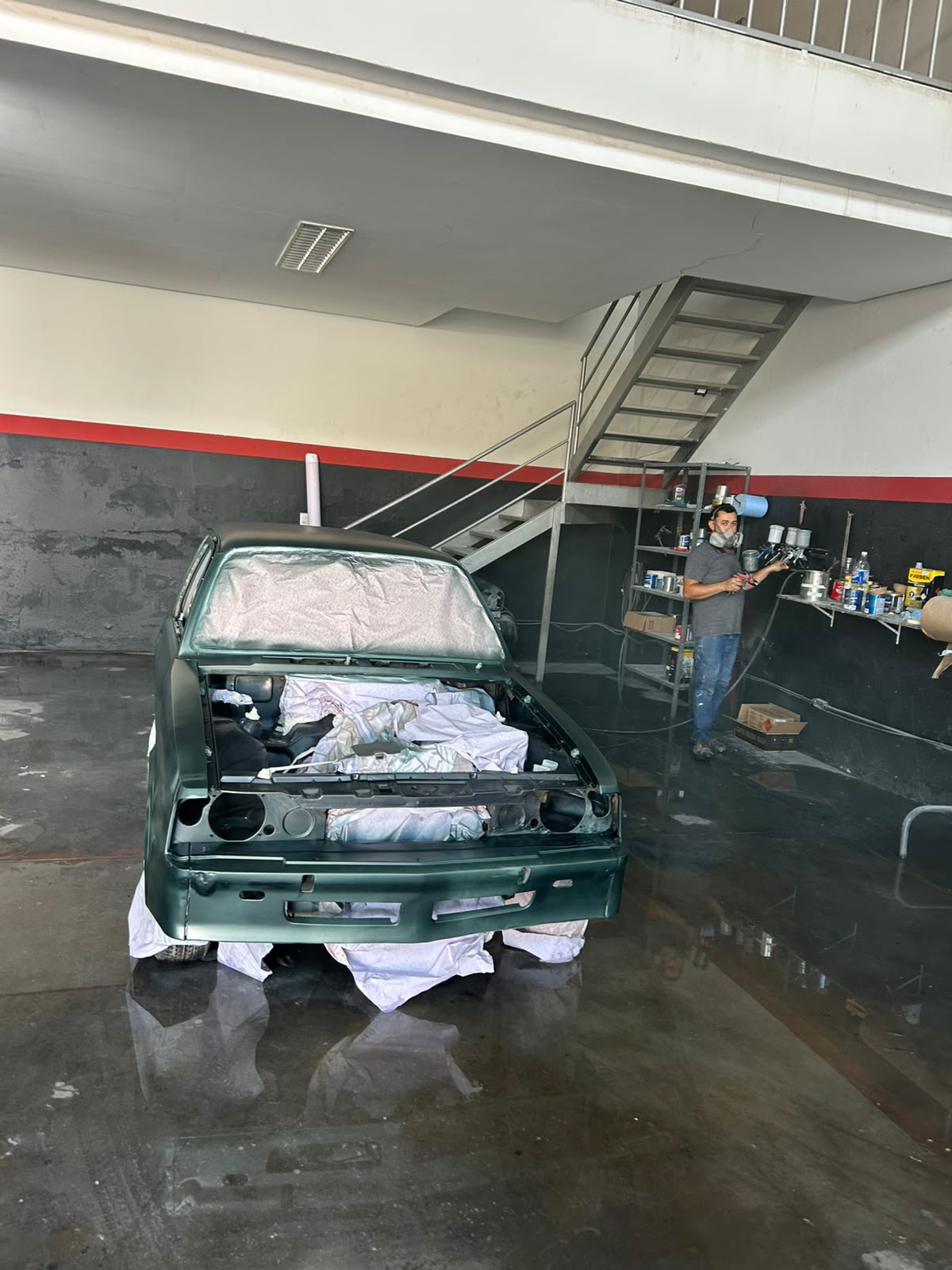 Carro verde em processo de pintura dentro da cabine