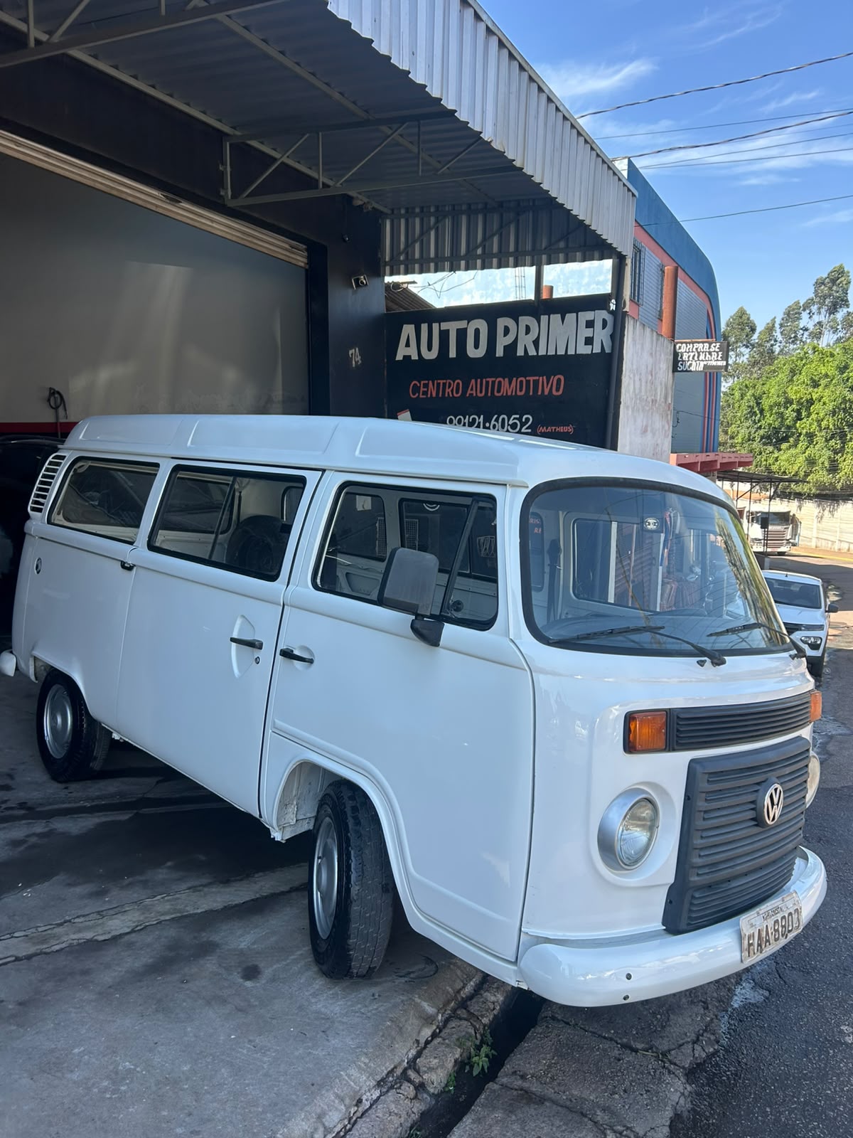 Kombi branca restaurada em frente à placa da Auto Primer